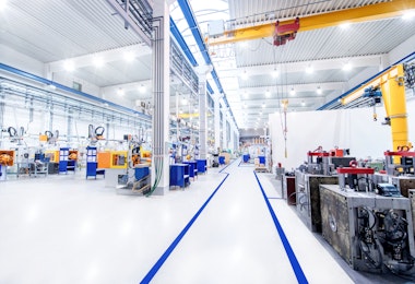 Horizontal image of huge new modern factory with robots and machines producing industrial plastic pieces and equipment. Wide angle view of futuristic machines and long aisle.