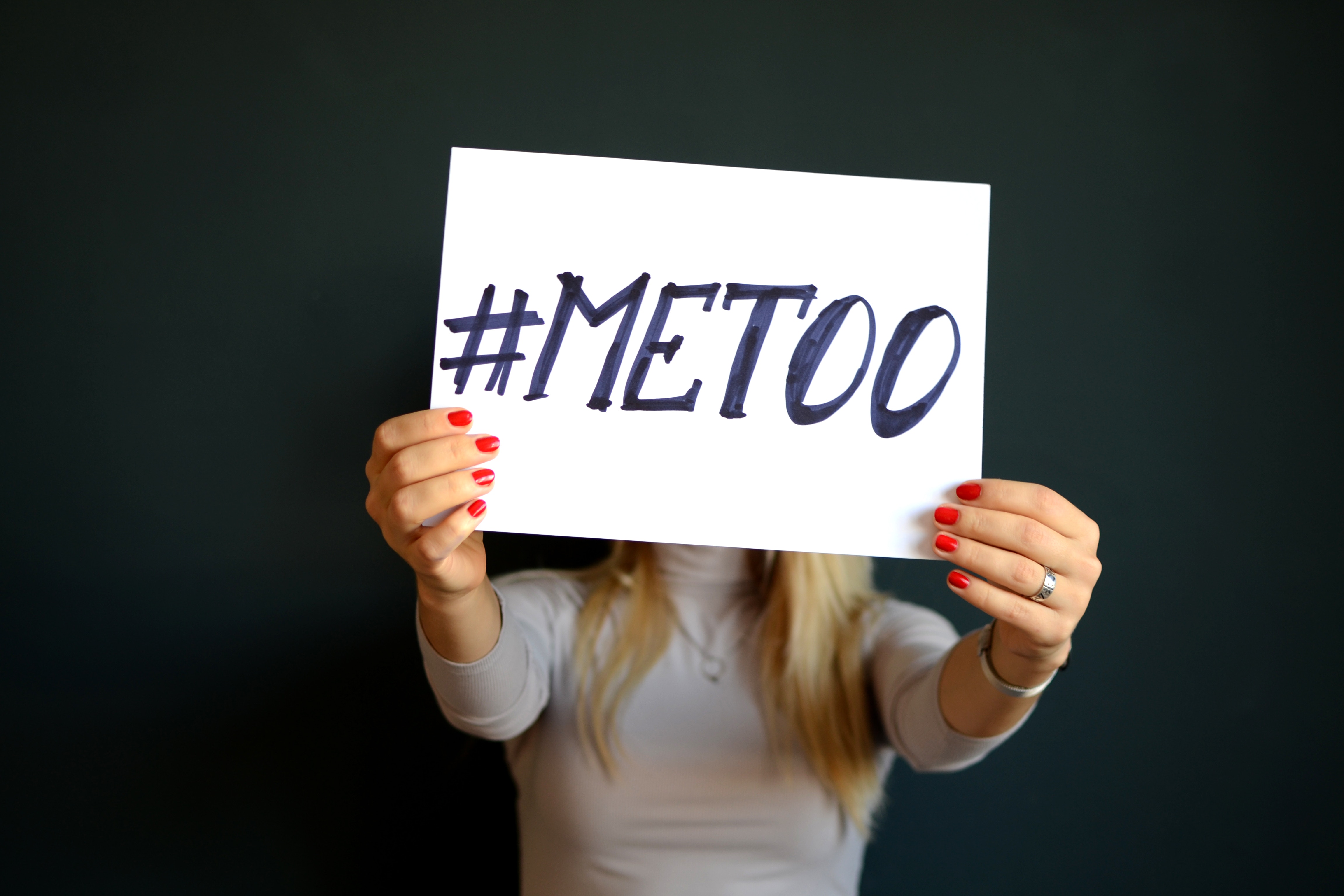 A woman holding up a sign that says #MEETOO