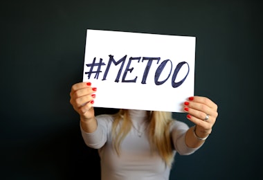 A woman holding up a sign that says #MEETOO