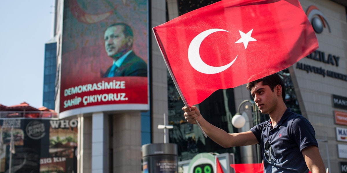 ANKARA, TURKEY - JULY 16: A man waves a Turkish flag from the roof of a car during a march around Kizilay Square in reaction to the attempted military coup on July 16, 2016 in Ankara, Turkey. Police regained control overnight after an attempted military coup against President Recep Tayyip Erdogan. The coup attempt claimed over 250 lives. President Erdogan urged his supporters to take to the streets in support to prevent any further flare ups.  (Photo by Chris McGrath/Getty Images)