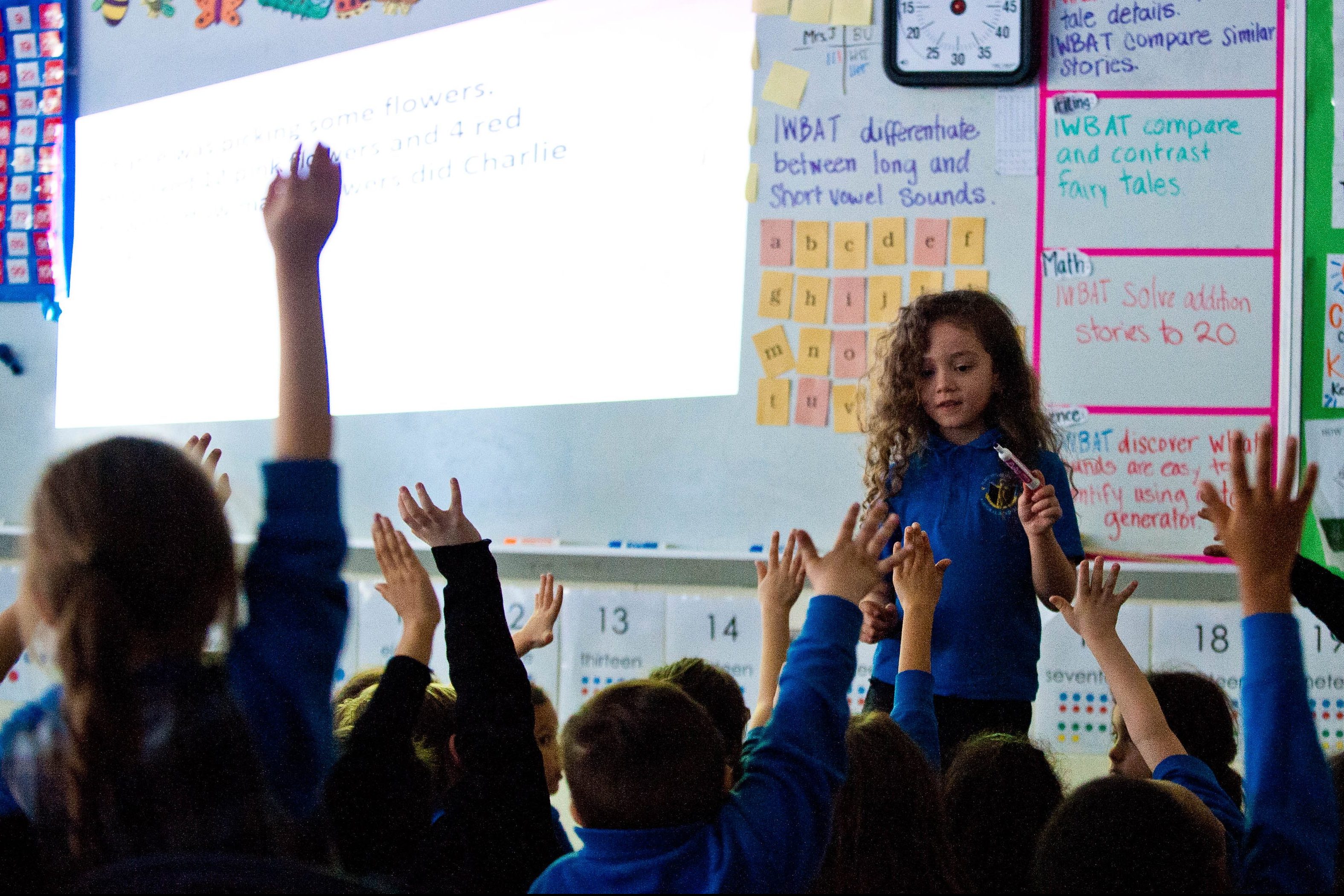 a group of children raising their hands in a classroom