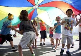 a group of young children standing under a colorful umbrella