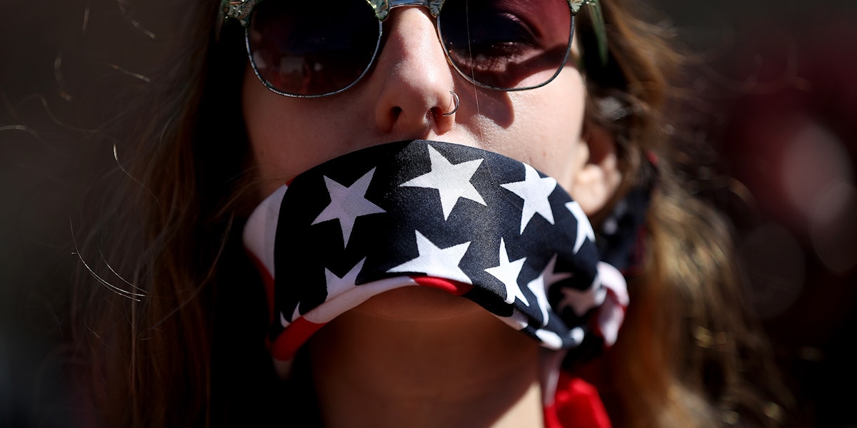 WASHINGTON, DC - MARCH 08:  A protester wears a patriotic bandana over her mouth during a march and rally to support women's health programs and protest the White House global gag rule on March 8, 2017 in Washington, DC. Hundreds of women marked International Women's Day with a march and rally outside of the White House to protest the White House global gag rule and support women's health programs.  (Photo by Justin Sullivan/Getty Images)