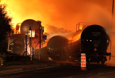 a train on a train track with a fire in the background