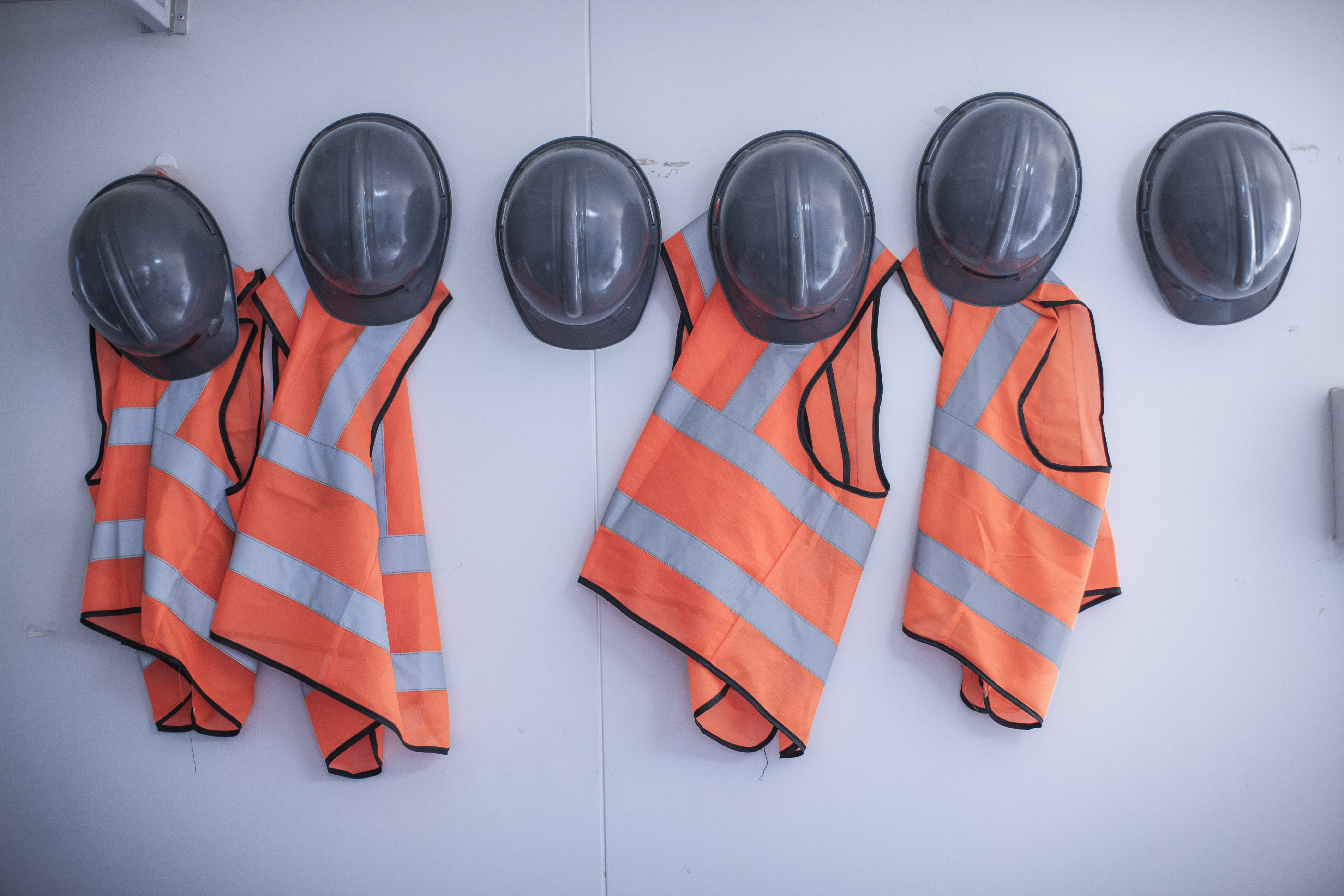 safety vests and hard hats hanging on wall in site office