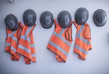 safety vests and hard hats hanging on wall in site office