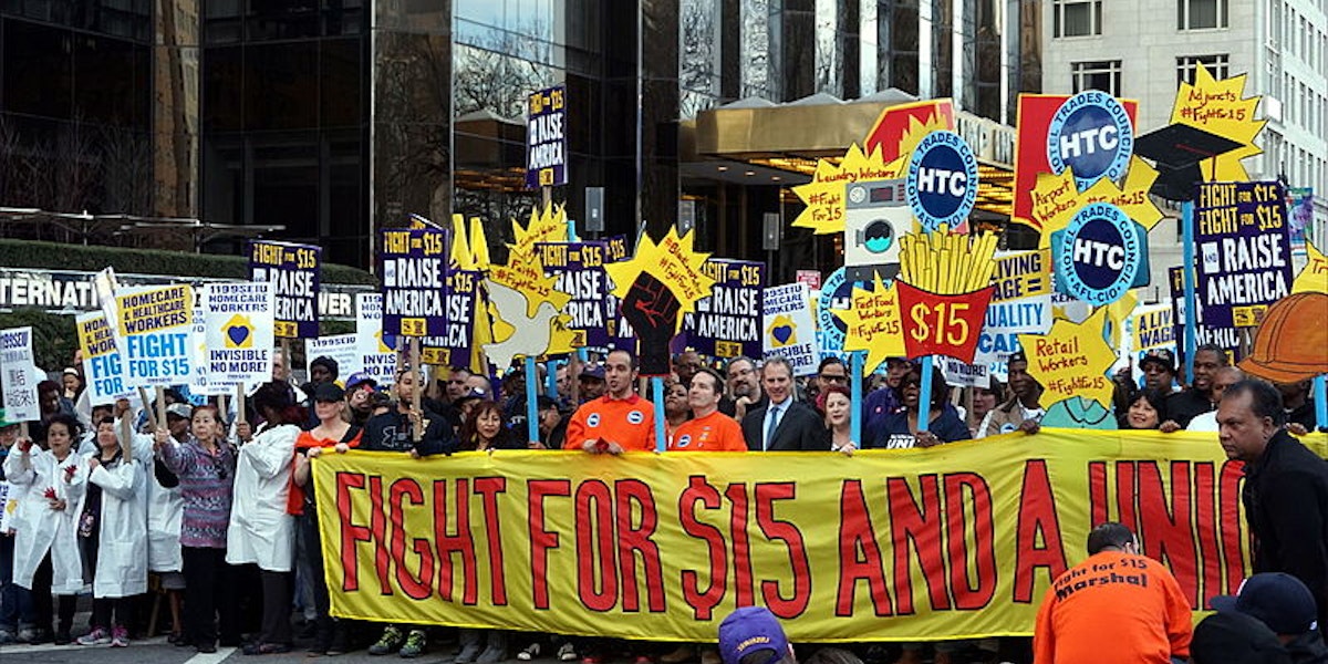 A photograph of a demonstration in a city advocating for the fight to raise the minimum wage.