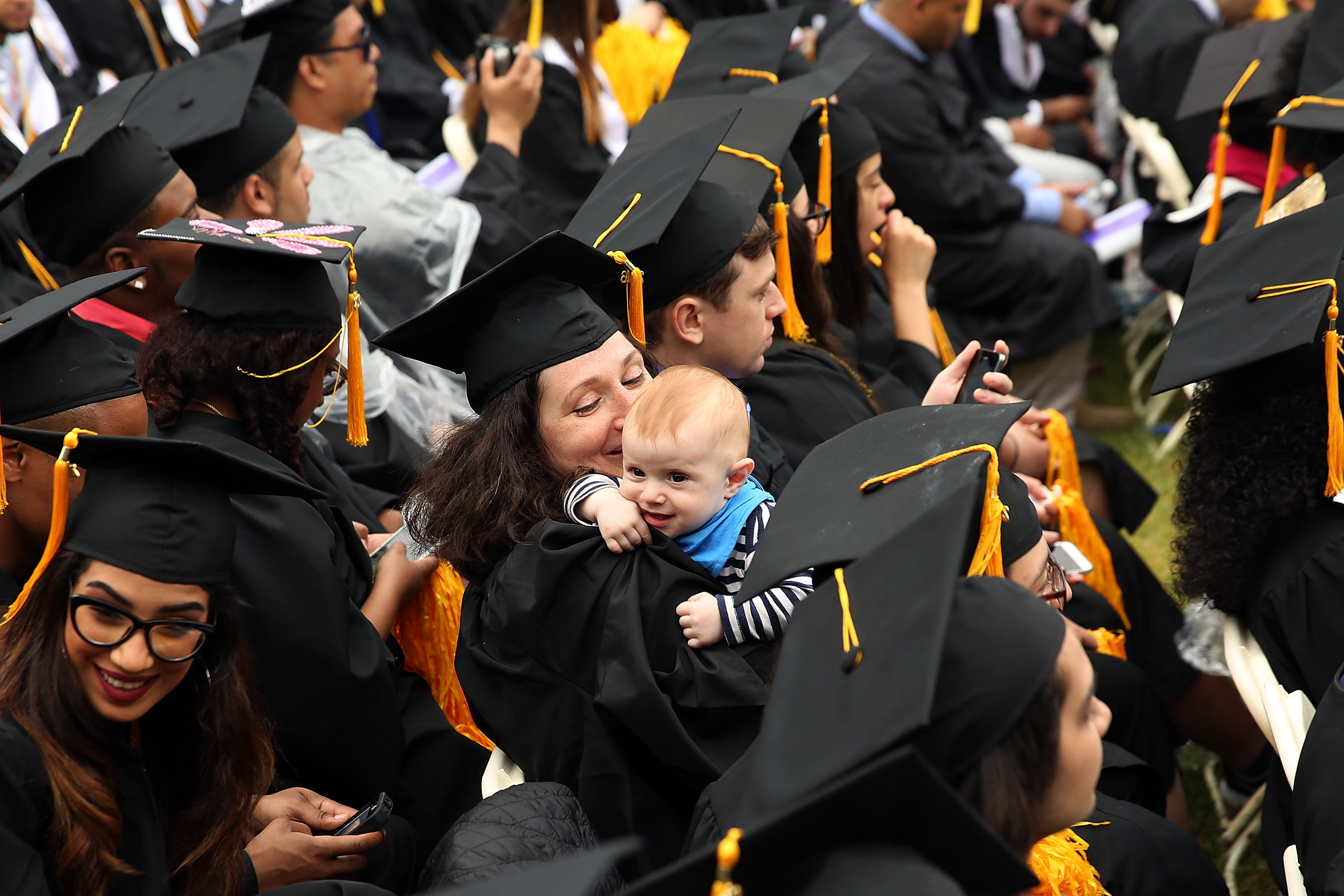 NEW YORK, NY - JUNE 03:  A graduating student holds her child as she participates in commencement exercises at City College where First lady Michelle Obama delivered the commencement speech after being presented with an honorary doctorate of humane letters at City College on June 3, 2016 in New York City. This is the final  commencement speech of her tenure as first lady. In her speech Mrs. Obama celebrated City College's diverse student body and the struggles that many students endured on the road to graduation.  (Photo by Spencer Platt/Getty Images)