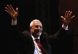 a man in a suit and tie raising his hands