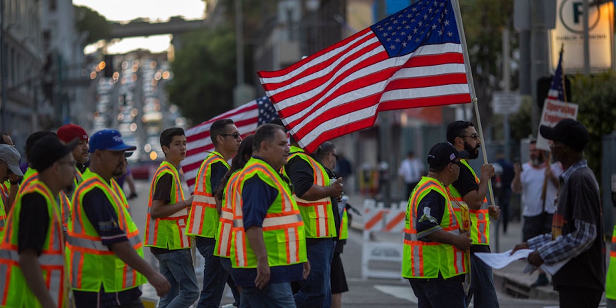 People walking with high visibility uniforms holding an american flag