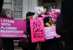 a group of people holding pink signs in front of a building
