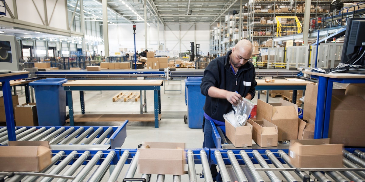 Male warehouse worker packing cardboard boxes for conveyer belt