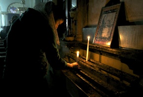 A worshipper lights a candle at the Syriac Orthodox Church in Al-Darbasiyah, Hasakah province November 13, 2013. Due to the clashes in north-eastern Syria, many Christians have fled the area seeking safety elsewhere, activists say. Picture taken November 13, 2013.  REUTERS/Stringer (SYRIA - Tags: CONFLICT RELIGION CIVIL UNREST) - GM1E9BF1K1001