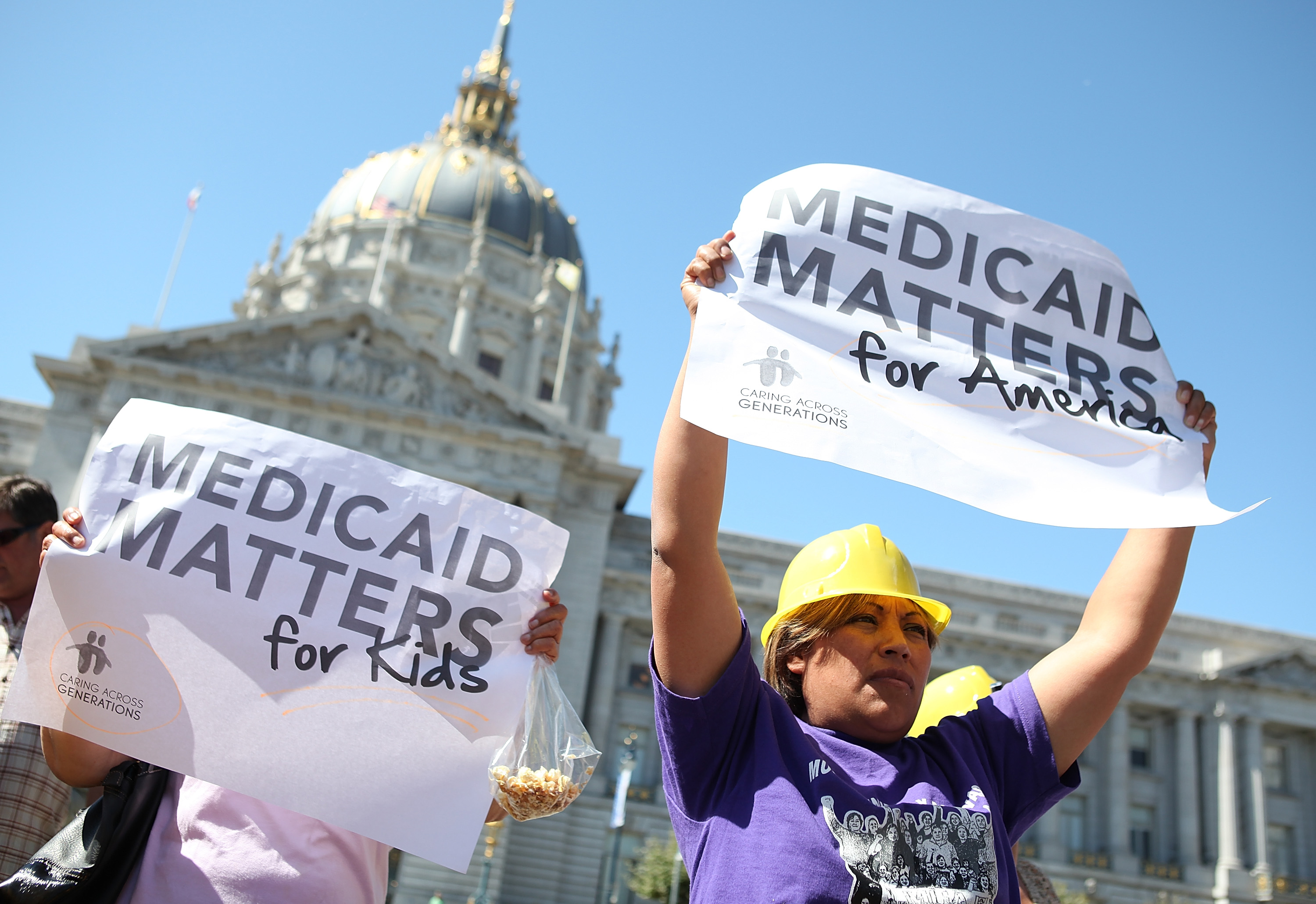 SAN FRANCISCO, CA - SEPTEMBER 21:  Protestors carry signs as they demonstrate against proposed cuts to Medical and Medicare outside San Francisco city hall on September 21, 2011 in San Francisco, California.  Dozens of disabled people staged a protest against proposed cuts to Medical, Medicare and Medicaid programs.  (Photo by Justin Sullivan/Getty Images)
