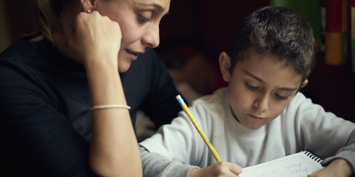 Hispanic mother watching son practicing writing alphabet