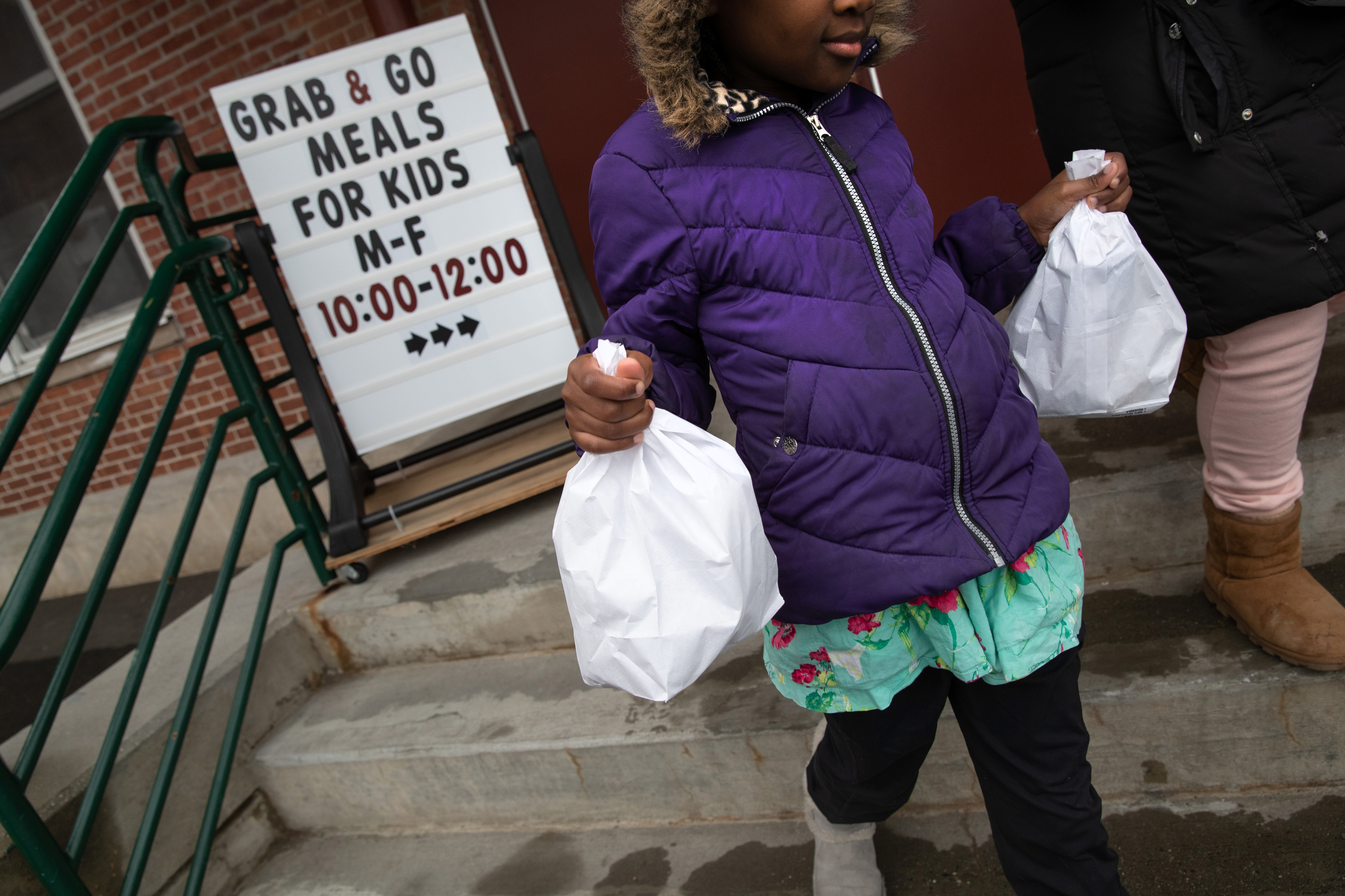 STAMFORD,  - MARCH 17: A student carries home bagged meals given out as part of Stamford Public Schools' 