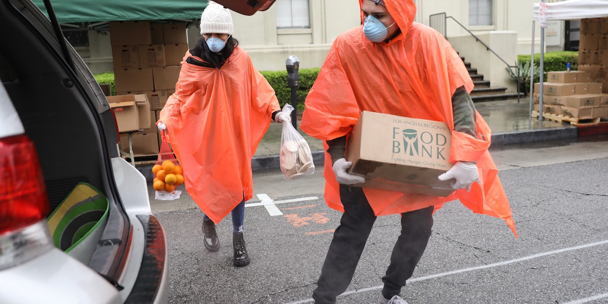 VAN NUYS, CALIFORNIA - APRIL 09: Volunteers load food into a recipient's trunk at a Food Bank distribution for those in need as the coronavirus pandemic continues on April 9, 2020 in Van Nuys, California. Organizers said they had distributed food for 1,500 families amid the spread of COVID-19. (Photo by Mario Tama/Getty Images)