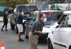HIALEAH, FLORIDA - APRIL 08: Eddie Rodriguez (R) and other City of Hialeah employees hand out unemployment applications to people in their vehicles in front of the John F. Kennedy Library on April 08, 2020 in Hialeah, Florida. The city is distributing the printed unemployment forms to residents as people continue to have issues with access to the state of Florida’s unemployment website in the midst of widespread layoffs due to businesses closing during the coronavirus pandemic. (Photo by Joe Raedle/Getty Images)