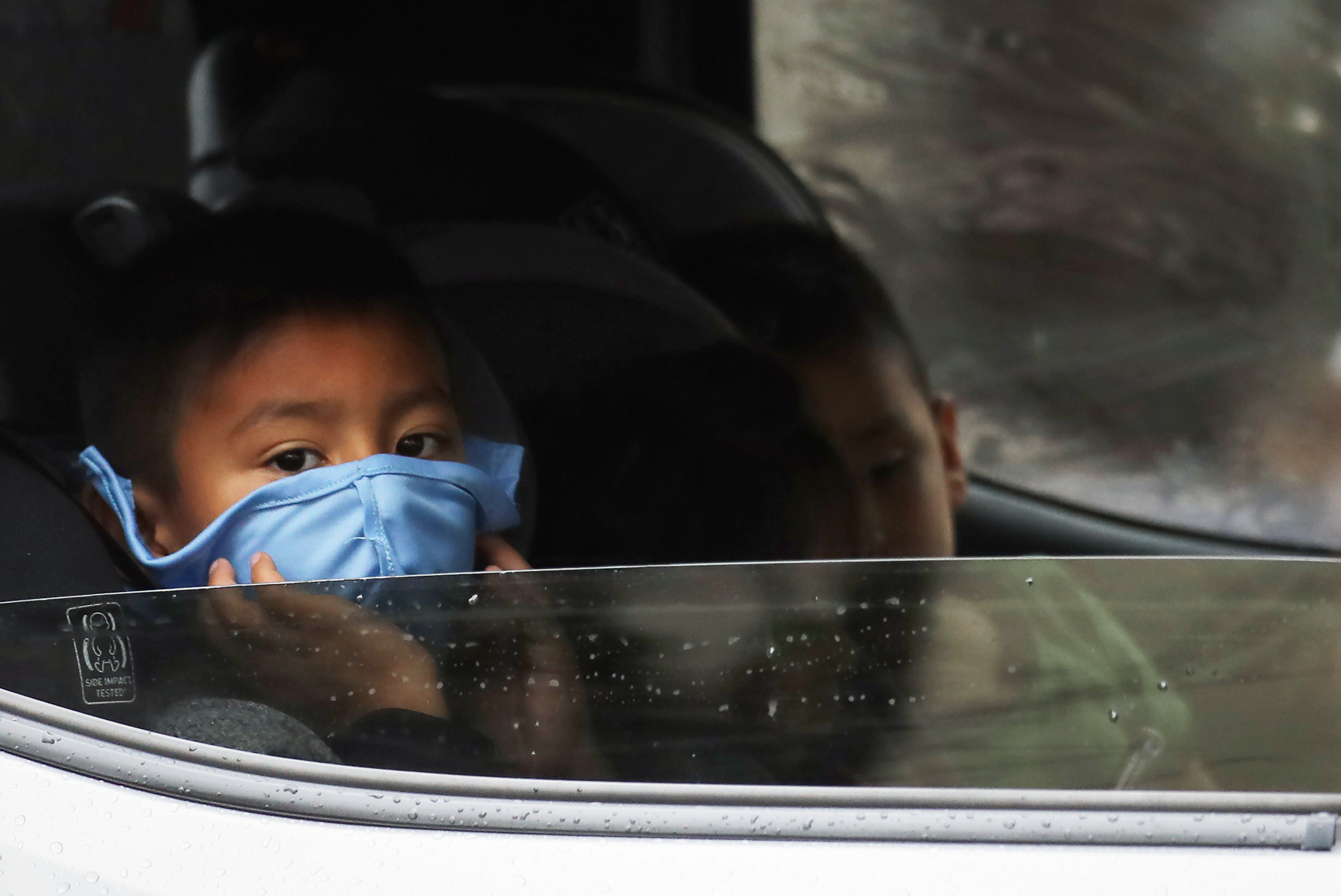 VAN NUYS, CALIFORNIA - APRIL 09: A boy wears a face mask as food is delivered to his truck at a Food Bank distribution for those in need as the coronavirus pandemic continues on April 9, 2020 in Van Nuys, California. Organizers said they had distributed food for 1,500 families amid the spread of COVID-19.  (Photo by Mario Tama/Getty Images)