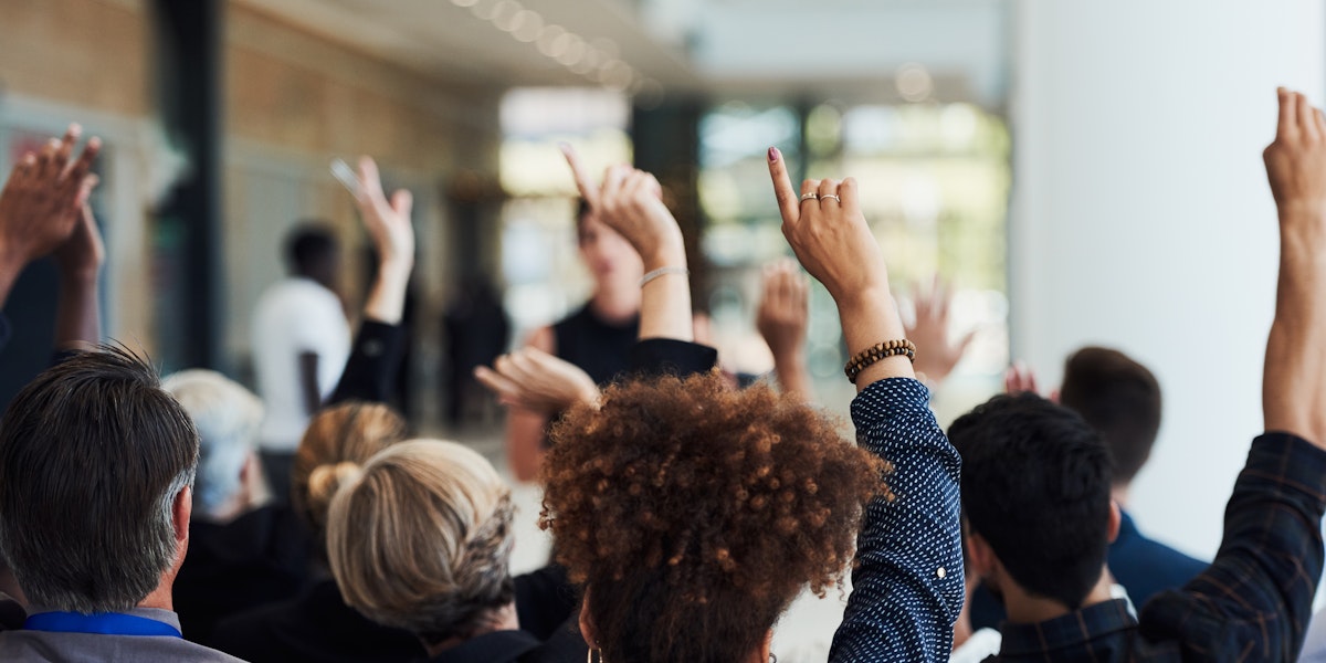 Shot of a group of businesspeople raising their hands to ask questions during a conference