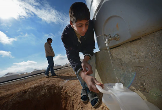 MAFRAQ, JORDAN - JANUARY 29: Syrian refugees gather water as they go about their daily business in the Za’atari refugee camp on January 29, 2013 in Mafraq, Jordan. Record numbers of refugees are fleeing the violence and bombings in Syria to cross the borders to safety in northern Jordan and overwhelming the Za'atari camp. The Jordanian government are appealing for help with the influx of refugees as they struggle to cope with the sheer numbers arriving in the country. (Photo by Jeff J Mitchell/Getty Images)