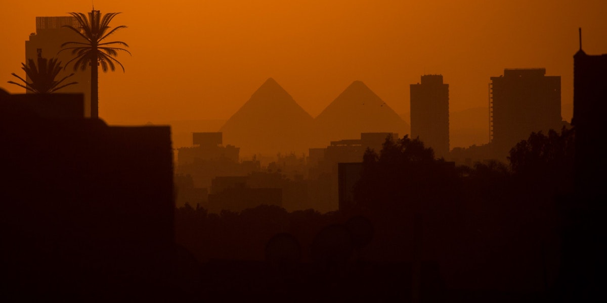 CAIRO, EGYPT - DECEMBER 15: City buildings are seen in front of the famous Giza Pyramids on December 15, 2016 in Cairo, Egypt. Since the 2011 Arab Spring, Egyptians have been facing a crisis, the uprising brought numerous political changes, but also economic turmoil, increased terror attacks and the unravelling of the once strong tourism sector. In recent weeks Egypt has again been hit by multiple bomb blasts, the most recent killed 26 Christians inside the St Peter and St Paul Church during Sunday mass. As Christians took to the streets chanting anti-government slogans, fears grow of an escalation in militant activity which would further deal damage to a country trying to rebuild. In recent months protests against rising fuel and food prices, calls for mass anti-government demonstrations and the continued terror attacks have seen Egyptian president Abdel Fattah Al-Sisi, suffer a significant drop in popularity. Mr. Al-Sisi has promised change, fearing anger and desperation could lead to popular unrest, however inflation currently sits at the highest level in seven years, jobless rates are above 13percent and more than 90million people are said to be living in poverty. The outlook forced the government to seek a $12 billion bailout from the International Monetary Fund, pushing the country to float the Egyptian pound to qualify for the loan. The move led to a sharp devaluation of the Egyptian pound which now sits at 18EGP to the dollar. The turmoil is affecting not only the poor but both the middle-class and the wealthy as food and commodity prices skyrocket.  (Photo by Chris McGrath/Getty Images)