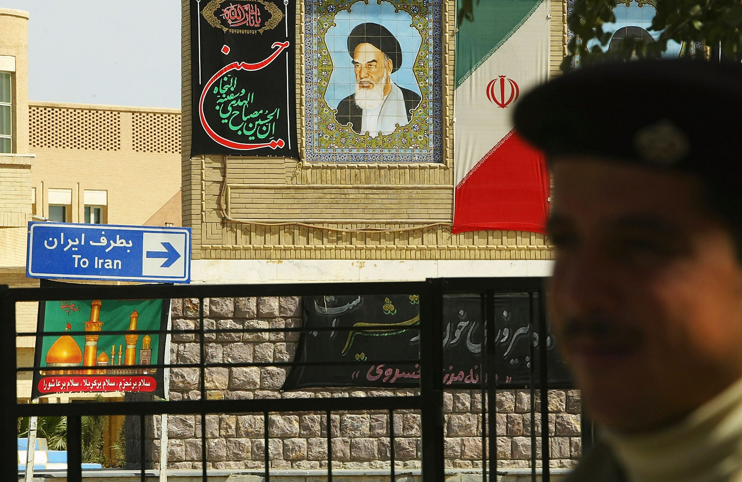 AL-MUNTHRIYA, IRAQ - MARCH 15:  An Iraqi border guard stands in front of a picture of the late Iranian leader Ayatollah Khomeini, which is displayed on the Iranian side March 15, 2004 at the Al-Munthriya border crossing in Al-Munthriya, Iraq.  The US has begun tightening security over Iraq's 1,300km border with Iran over the weekend, as six more US servicemen were killed in attacks by forces opposed to the 11-month old occupation. Currently there are 19 legal crossing points between Iraq and Iran, but this will be reduced to three and each traveler will have to produce a passport and be registered, Paul Bremer, the senior US administrator in Iraq, announced Saturday. The number of Iraqi border guards are to be doubled to 16,000.  (Photo by Spencer Platt/Getty Images)