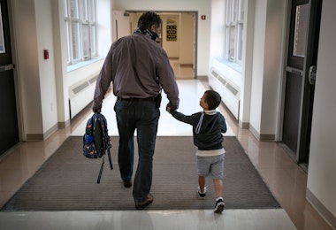 STAMFORD, CONNECTICUT - SEPTEMBER 16: Assistant principal Joe Claps escorts a child to class at Stark Elementary School on September 16, 2020 in Stamford, Connecticut. Most students at Stamford Public Schools are taking part in a hybrid education model, where they attend in-school classes every other day and distance learn the rest. About 20 percent of students in the school district, however, are enrolled in the distance learning option due to coronavirus concerns. (Photo by John Moore/Getty Images)