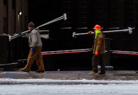 Photograph of construction workers carrying scaffolding beams