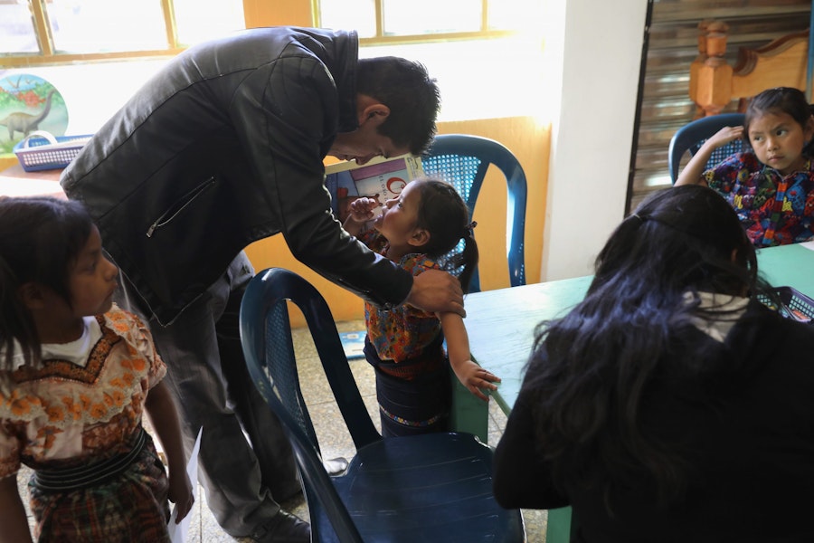 CAJOLA, GUATEMALA - FEBRUARY 12: Teacher Willy Jimenez talks with Indigenous Mayan Mam-speaking children at a reading circle held in the Grupo Cajola library on February 12, 2017 in Cajola, in the western highlands of Guatemala. Women are especially effected by emigration from Guatemala, where some 70 percent of the men have left to work as undocumented immigrants in the United States, many of them leaving behind wives and children who only know their fathers online, if at all. Grupo Cajola, an NGO funded by American donations, is attempting to make the town's economy prosper locally to help reduce the need for emigration. With U.S. President Donald Trump's crackdown on illegal immigration, the spectre of increased deportations back to Guatemala and reduced remittances has made the need to educate children and adults and transform the local economy more urgent than ever. Remitances from undocumented Guatemalan laborers are the main source of income of Guatemala, and while increasing wealth and driving a housing boom in towns like Cajola, they have also had the negative effect tearing the social fabric of local communites. Grupo Cajola has set up a weaving center, an egg farm, carpentry shop, internet cafe, library and education programs for pre-schoolers and their parents, while providing scholarships for more than 20 young residents to learn local trades. Textiles they produce are now exported for sale to the U.S. The NGO was founded in 2000 by Eduardo Jimenez, who lived as an undocumented immigrant for 10 years in the U.S. before returning to Guatemala. He coordinates locally with the group's American director Caryn Maxim, who organizes funding and product sales in New Jersey.  (Photo by John Moore/Getty Images)