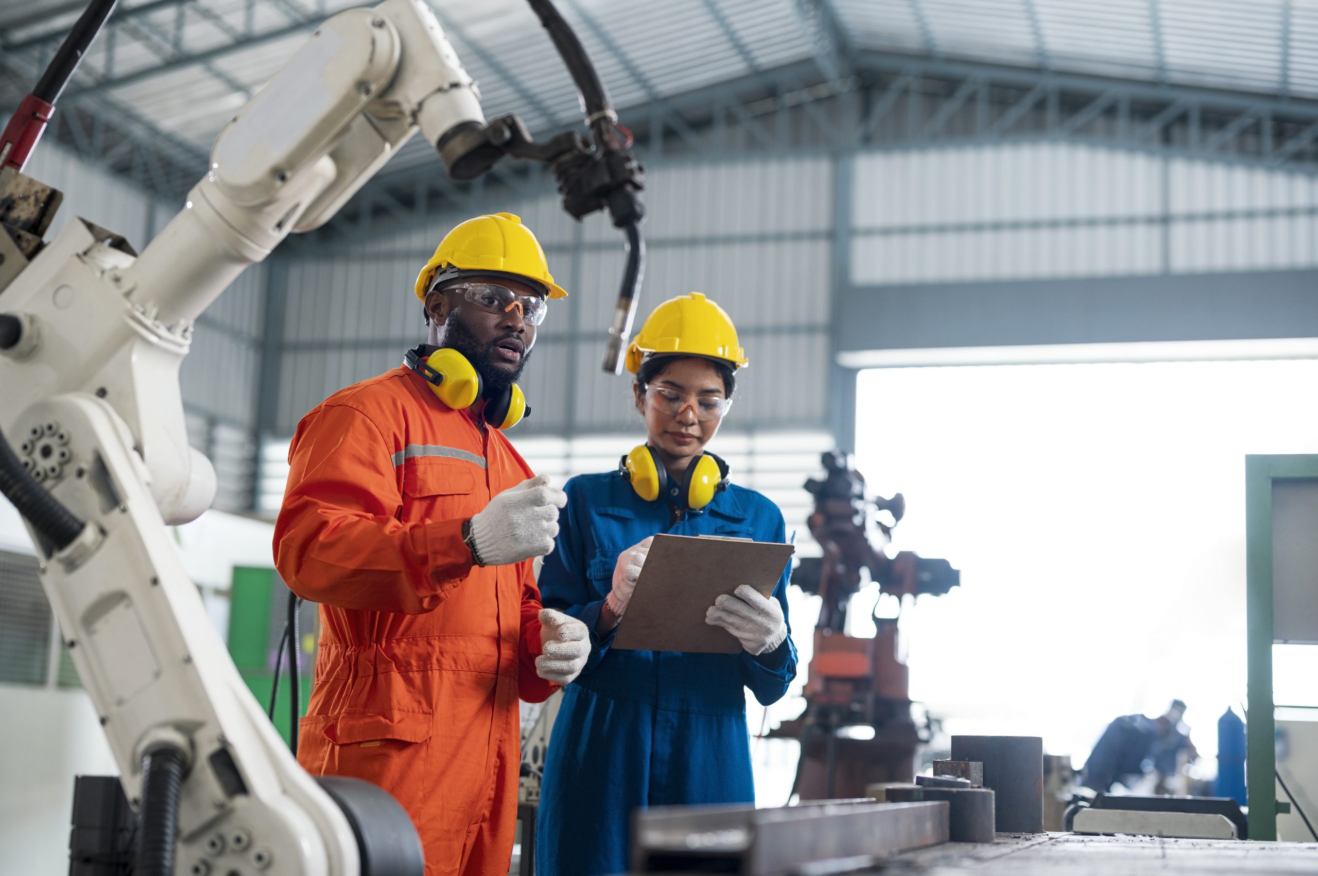 Robotic safety checklist audit concepts. Multi-Ethnic Engineers is analyzing the work process of industrial robotics welding to collect data to improve work processes.