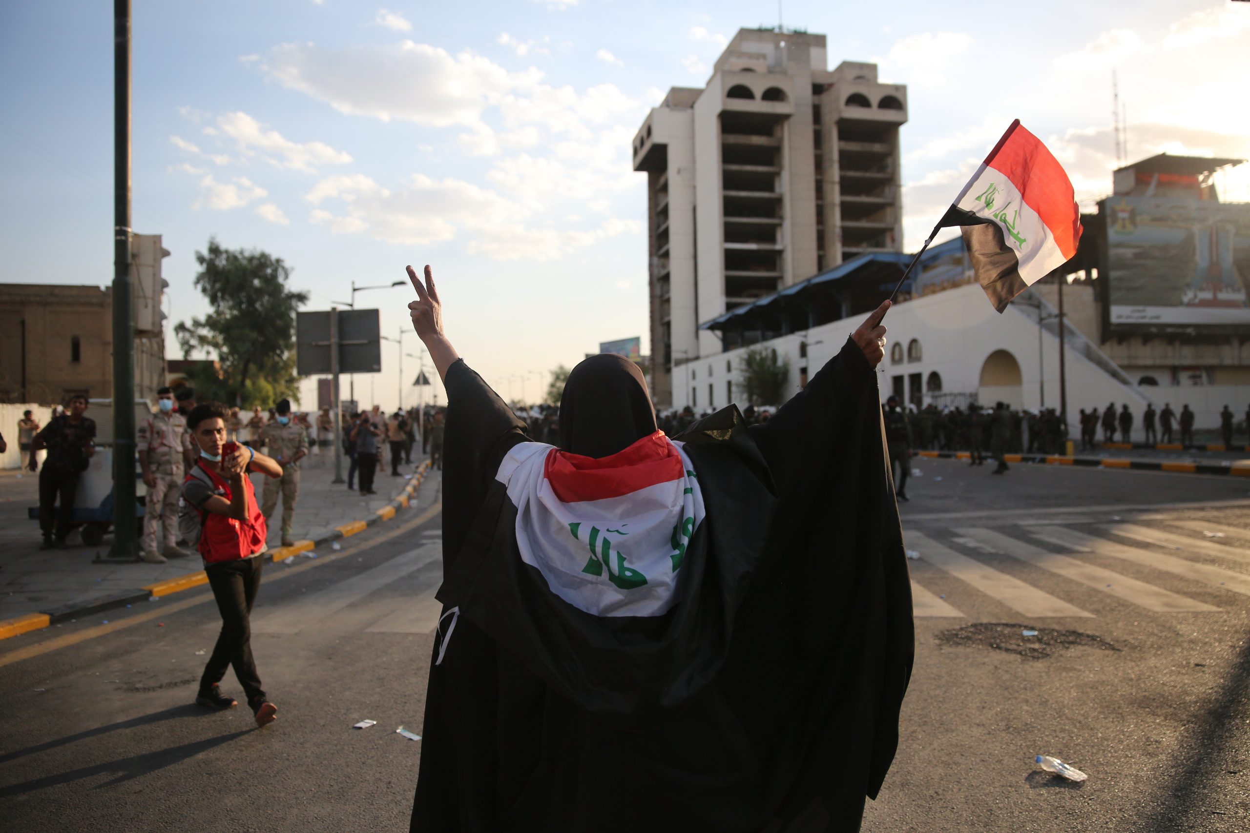 BAGHDAD, IRAQ - MAY 25: woman waiving Iraqi flag and trying to stop Riot police after rushing towards protesters  on May 25, 2021 in Baghdad, Iraq. Protesters from across the country gathered in Baghdad demanding accountability after a recent rise in targeted assassinations. The protests used the slogan 'Who killed me' to highlight the recent killings of activists, journalists and human rights advocates. (Photo by Taha Hussein Ali/Getty Images)