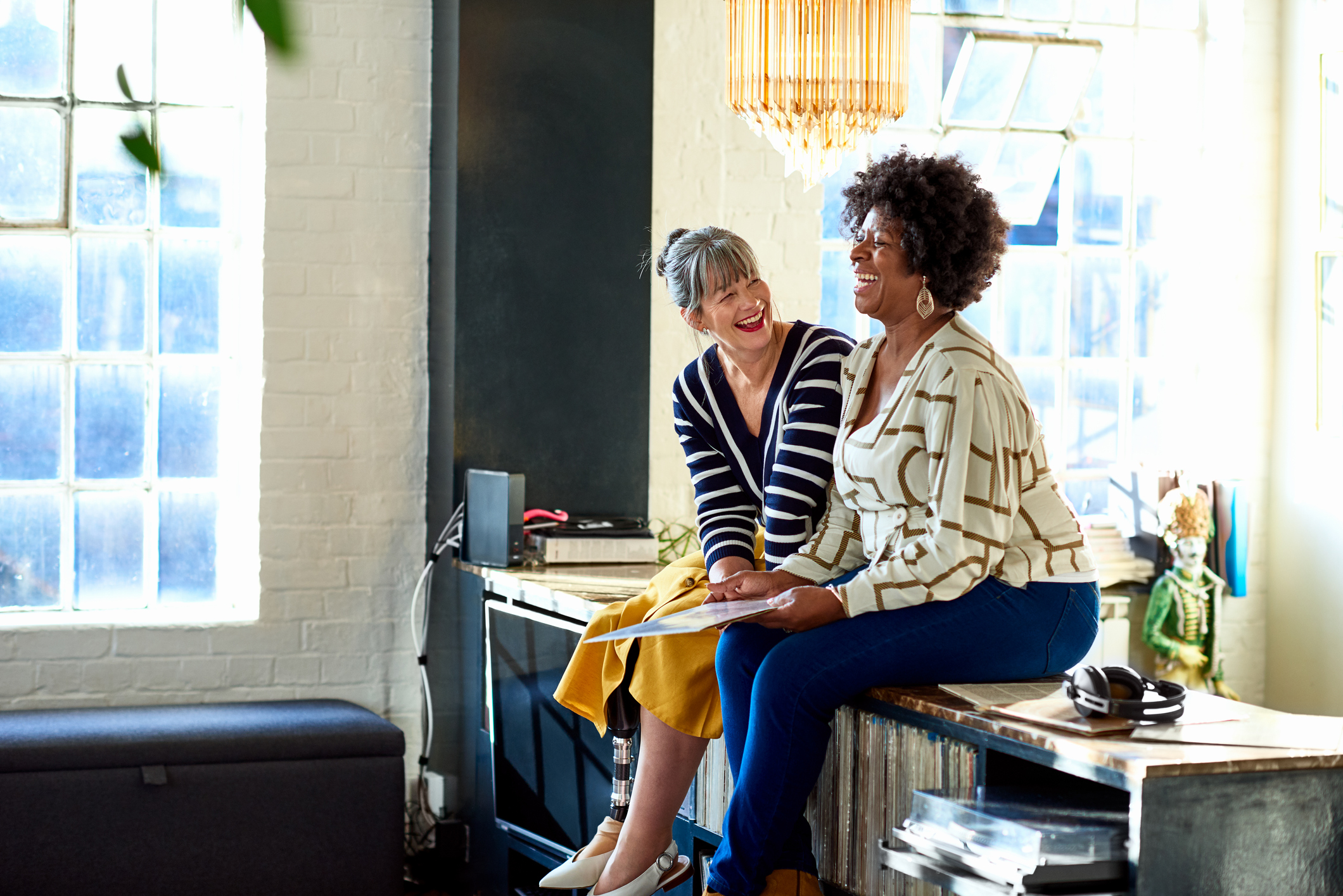 Two female friends sitting on sideboard and smiling, friendship, fun, memories, wellbeing