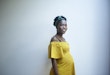 Indoors portrait of a beautiful pregnant woman, dressed in yellow.