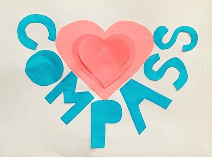 Children's artwork with a pink heart and the word Compass cut out of construction paper.