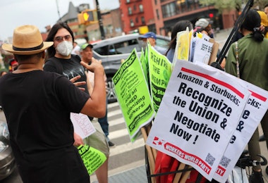 NEW YORK, NEW YORK - APRIL 14: People hold signs while protesting in front of Starbucks on April 14, 2022 in New York City. Activists gathered to protest Starbucks' CEO Howard Schultz anti-unionization efforts and demand the reinstatement of workers fired for trying to unionize. (Photo by Michael M. Santiago/Getty Images)
