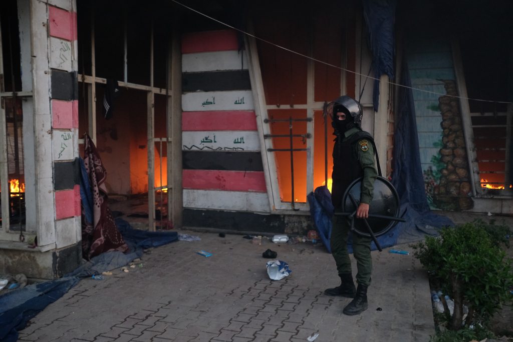Riot police check the headquarters of the riot police after it was set on fire by protesters in Baghdad’s Tahrir Square on May 25, 2021.