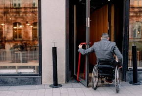 Rear view of disabled mature man sitting on wheelchair while entering in store.