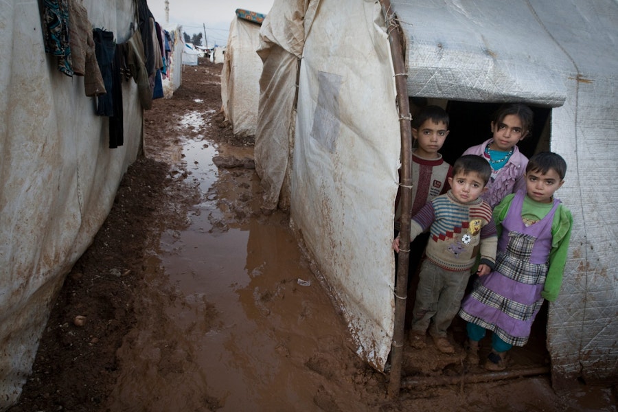 On 1 January, children stand in the entryway of their tent shelter, in the Bab Al Salame camp for internally displaced persons, near the border with Turkey, in Aleppo Governorate. A muddy and puddled walkway separates their tent from those of their neighbours. Laundry has been hung to dry nearby. Keeping clothing clean and dry has been a major challenge for residents. Residents have also expressed concern that hygiene conditions in the camp are worsening, increasing the risk of disease.

In early January 2014 in the Syrian Arab Republic, the ongoing conflict has affected some 9.3 million people. Of these, 6.5 million have been displaced internally. Syrians have also fled abroad, with more than 2.3 million people registered or awaiting registration with the United Nations High Commission for Refugees (UNHCR) in Egypt, Iraq, Jordan, Lebanon and Turkey. UNICEF support in the Syrian Arab Republic includes the distribution of clothing and other supplies to help keep children and their families healthy and warm during the winter; a polio vaccination campaign; the provision of primary health care services via both mobile medical teams and fixed centres; initiatives in water, sanitation and hygiene, including efforts to ensure continuous access to safe water in conflict-prone areas; the distribution of school supplies; and the provision of psychosocial support services for children and adolescents. United Nations agencies, including UNICEF, have appealed for US$6.5 billion to cover responses within the Syrian Arab Republic and host countries between January and December 2014. The appeal includes some US$2.3 billion for the 2014 Syrian Arab Republic Humanitarian Assistance Response Plan led by the Office for the Coordination of Humanitarian Affairs (OCHA) to aid people inside Syria and US$4.2 billion for the UNHCR-led Syria Regional Response Plan to aid refugees and host communities.