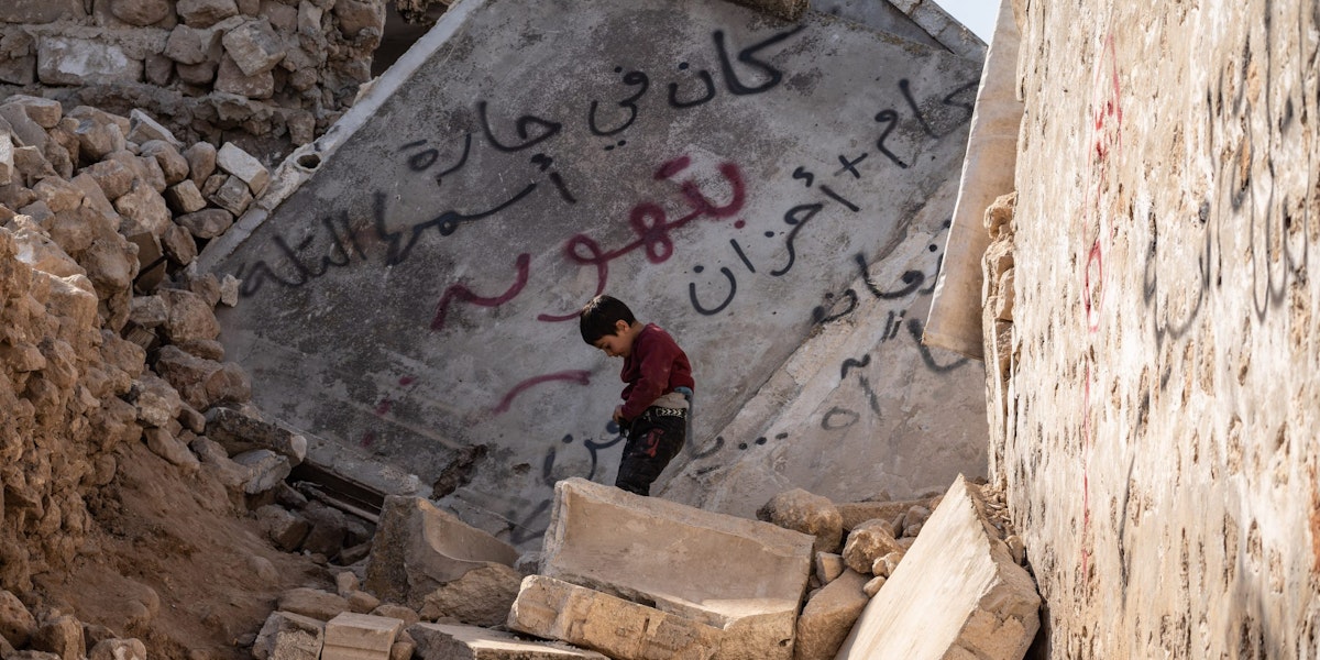 IDLIB, SYRIA - February 24: A Syrian child walks through a destroyed house, written on the wall “here it was a lane called Tal” following the earthquake, in the city of Armanaz , on February 24, 2023 in Idlib, Syria. According to locals more than two million people who have been displaced because of war lived in the northwest of Syria before the earthquake. A 7.8-magnitude earthquake hit near Gaziantep, Turkey, in the early hours of February 6, followed by another 7.5-magnitude tremor just after midday. The quakes caused widespread destruction in southern Turkey and northern Syria and has killed more than 40,000 people. (Photo by Abdulmonam Eassa/Getty Images)