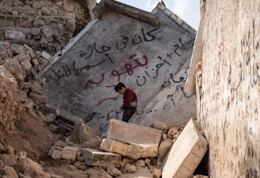 IDLIB, SYRIA - February 24: A Syrian child walks through a destroyed house, written on the wall “here it was a lane called Tal” following the earthquake, in the city of Armanaz , on February 24, 2023 in Idlib, Syria. According to locals more than two million people who have been displaced because of war lived in the northwest of Syria before the earthquake. A 7.8-magnitude earthquake hit near Gaziantep, Turkey, in the early hours of February 6, followed by another 7.5-magnitude tremor just after midday. The quakes caused widespread destruction in southern Turkey and northern Syria and has killed more than 40,000 people. (Photo by Abdulmonam Eassa/Getty Images)