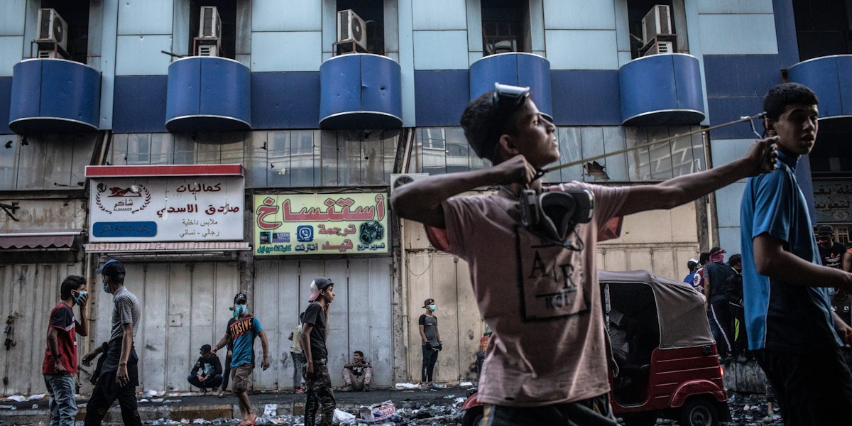 BAGHDAD, IRAQ - NOVEMBER 15: A young Iraqi protestor lauches rocks with a slingshot at Iraqi security forces near Al-Senak bridge on Nov. 15, 2019 in Baghdad, Iraq. Al-Senak bridge has been a contested area where protestors have continued to advance their movements pushing northwest as Iraqi security forces aim to maintain their position. Since Oct. 1, thousands of demonstrators have occupied various parts of Baghdad including its main bridges and Tahrir Square calling for government and policy reform. For many, Tahrir Square, which protesters are calling