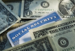 Studio shot of social security card nestled between dollar bills.