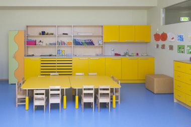 Classroom in a kindergarten school, yellow furniture and tables and blue floor.