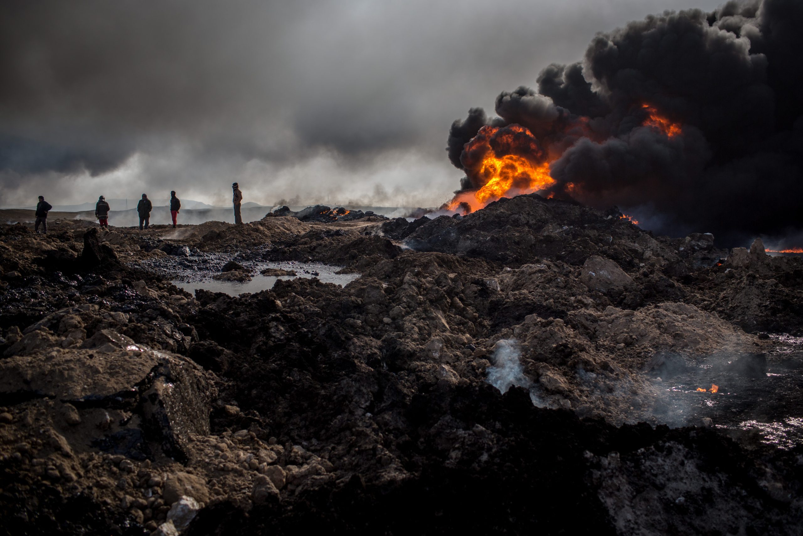 QAYYARAH, IRAQ - DECEMBER 23:  Fire crews work to extinguish a burning oil well on the outskirts of Qayyarah on December 23, 2016 in Qayyarah, Iraq. The fire crews, brought in from Kirkuk, have been working tirelessly with oil company representatives to extinguish the oil wells set ablaze by Daesh on their retreat from the city more than two months ago. The fire crews are currently working on their ninth oil well after extinguishing nearly all the wells close to the city.  (Photo by Chris McGrath/Getty Images)