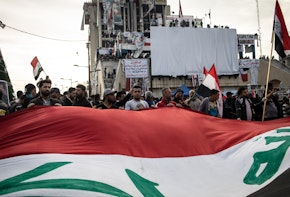 BAGHDAD, IRAQ - NOVEMBER 22: Demonstrators wave a large flag in Tahrir Square on Nov. 22, 2019 in Baghdad, Iraq. Thousands of demonstrators have occupied Baghdad's center Tahrir Square since October 1, calling for government and policy reform. For many, Tahrir Square - which demonstrators are calling 