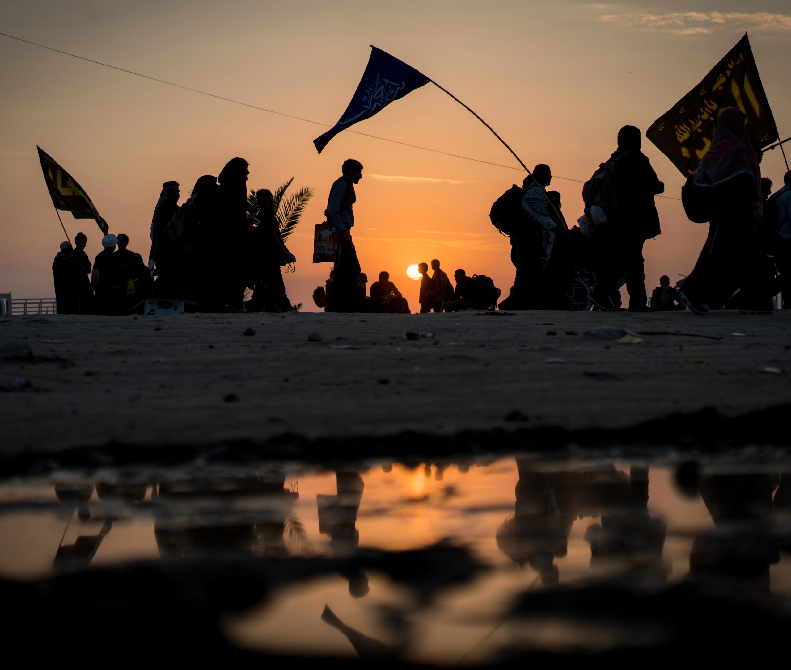 Silhouettes of crowded people walking at sunset time toward Karbala in Iraq for visiting the Holy Shrine of Imam Hussain