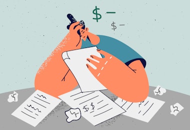 A person sitting at a table, clearly distressed by a pile of bills.