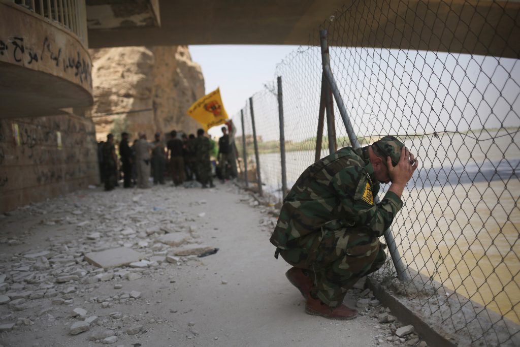 A Badr Brigade militia soldier mourns along the Tigris River in Tikrit on April 9, 2015. The Islamic State massacred Iraqi army recruits at Camp Speicher in Tikrit, with many shot and pushed into the river, less than a year earlier. Source: John Moore/Getty Images
