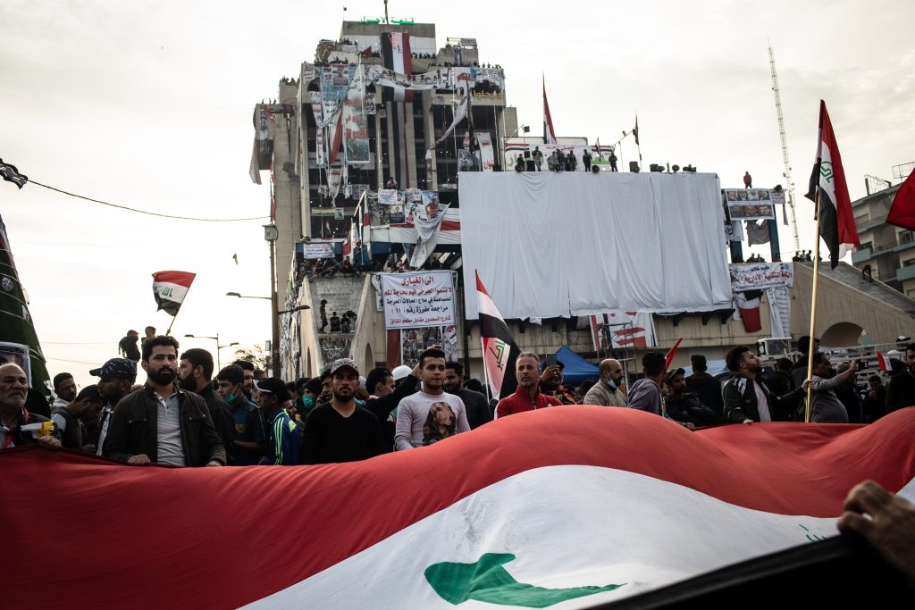 Demonstrators wave a large flag in Tahrir Square on November 22, 2019 in Baghdad, during the Tishreen movement protests. Source: Erin Trieb/Getty Images